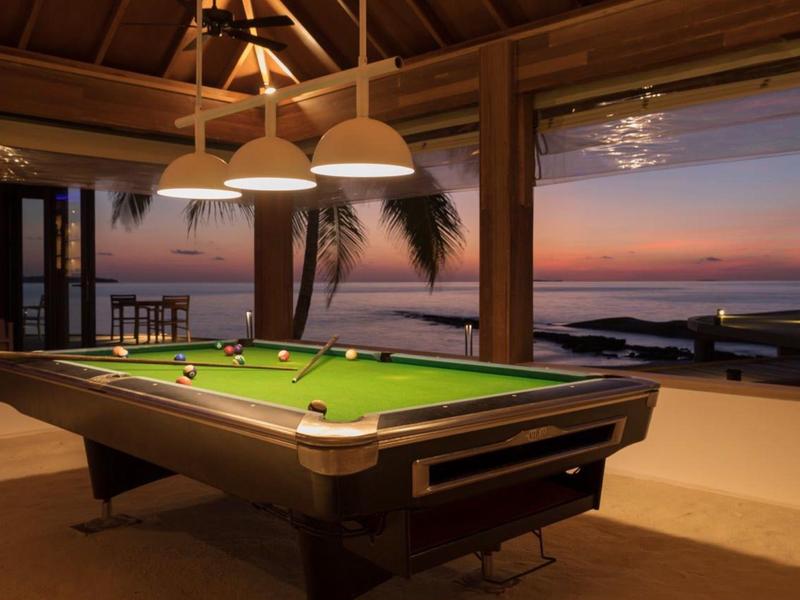 Tavolo da biliardo in una lounge aperta con vista sul mare al tramonto.