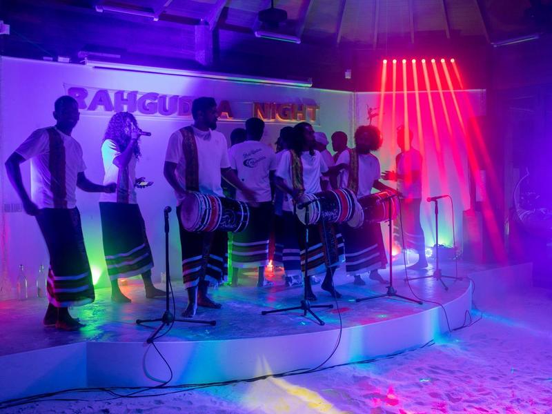 Gruppo di cantanti su un palco con luci colorate in una sala eventi.