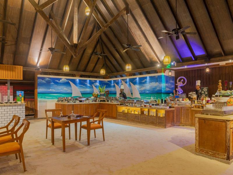 Ampia sala da pranzo dell'hotel con soffitto in legno, più tavoli e stazioni buffet.