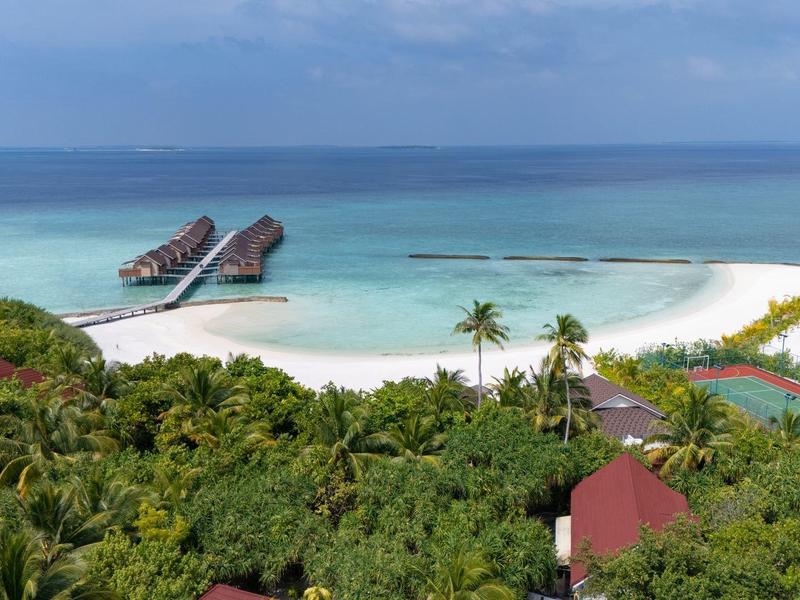 Isola tropicale con palme, spiaggia sabbiosa e molo con due barche nel mare blu