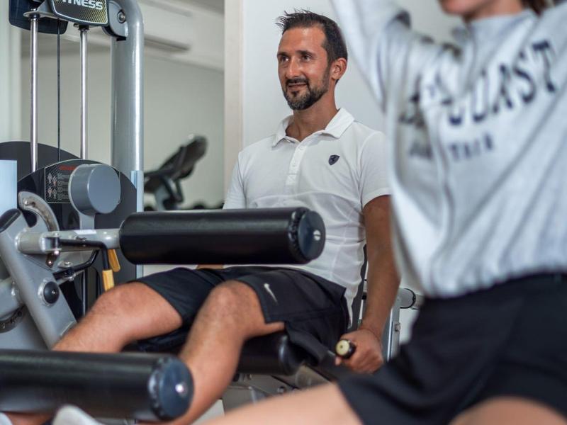Uomo e donna si allenano insieme su macchine per la forza in palestra.