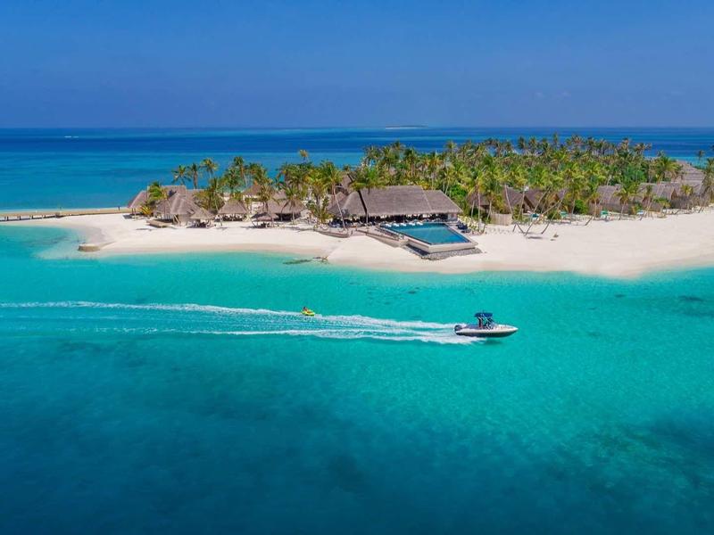Kleine tropische Insel mit weißem Sandstrand, Palmen und Boot im türkisblauen Meer.