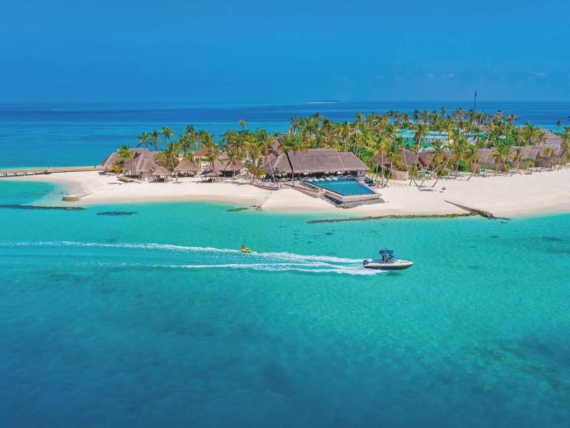 Kleine tropische Insel mit palmenbewachsenem Strand und klarem türkisfarbenem Wasser im Ozean.