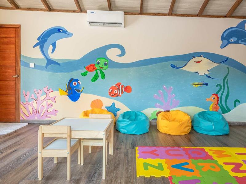 Kinderzimmer mit buntem Wandgemälde von Meerestieren, kleinen Möbeln und Sitzsäcken.