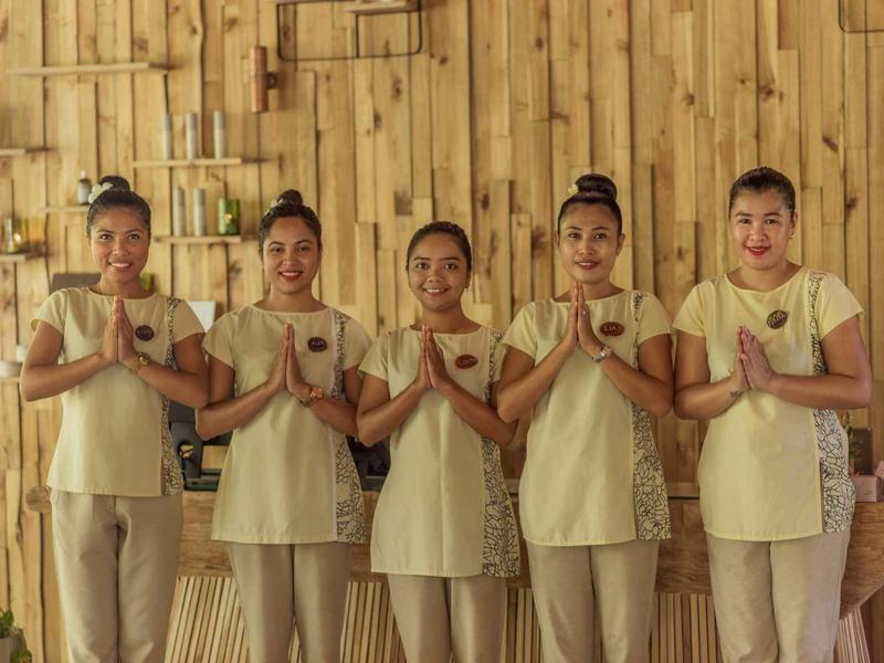 Fünf Frauen in beigen Uniformen stehen nebeneinander und halten die Hände vor der Brust.