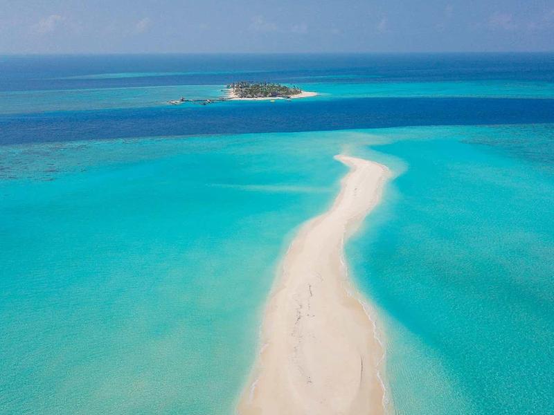 Sandbank mit weißem Sand und türkisfarbenem Meer unter klarem, blauem Himmel.