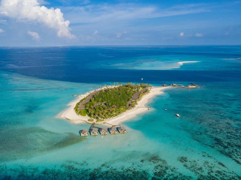 Kleine tropische Insel mit Palmen, Sandstränden und klarem türkisblauem Wasser.