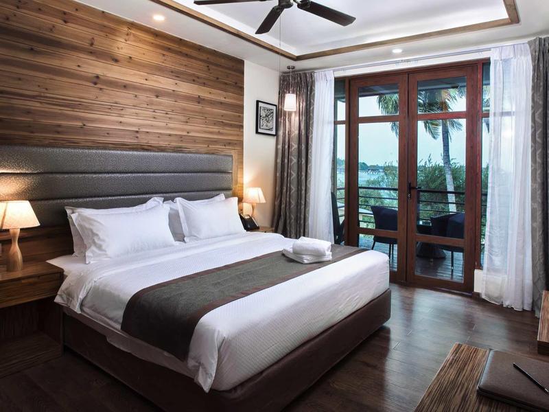 Nowoczesna sypialnia z dużym łóżkiem, drewnianymi ścianami i balkonem z widokiem na jezioro.