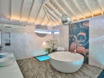 Luxe badkamer met vrijstaand bad, wastafels, discobal en helderig plafond.
