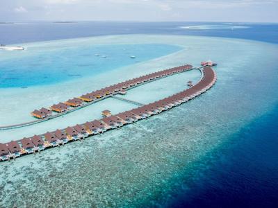 Luchtfoto van watervilla's op palen boven turquoise zee in een tropisch resort.
