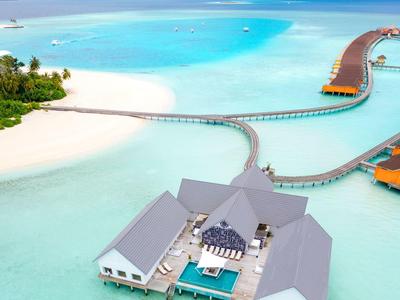 Luxe watervilla's met bruggen over turquoise water en wit zandstrand.
