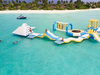 Opblaasbaar waterpark met glijbanen en klimwand in helderblauwe zee bij tropisch strand