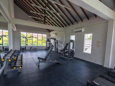 Modern gym with weights and exercise machines in a bright room with exposed beams.