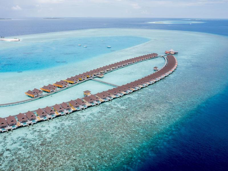 Luchtfoto van watervilla's op palen boven turquoise zee in een tropisch resort.