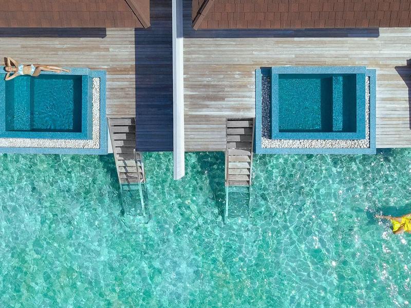 Luchtfoto van twee waterbungalows met privézwembaden en directe toegang tot de zee.
