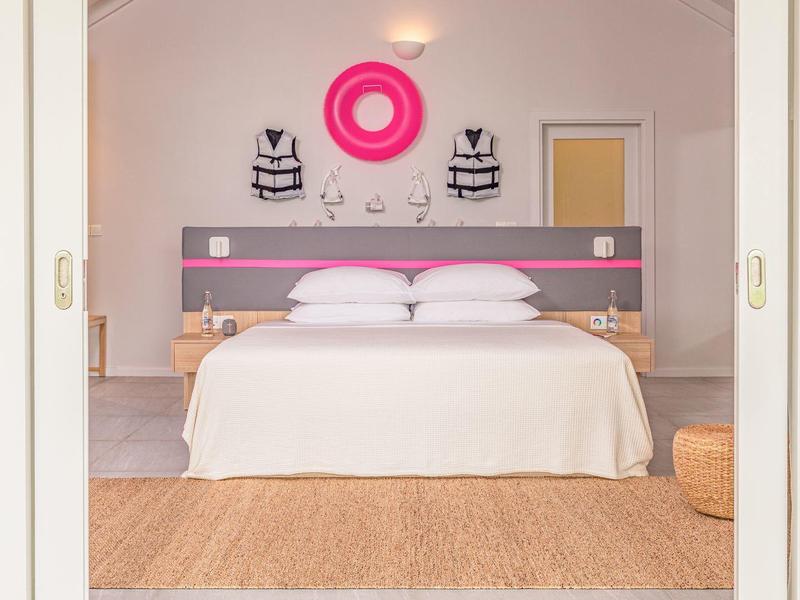 Modern hotelkamer met tweepersoonsbed en smaakvolle wanddecoratie in zachte kleuren.