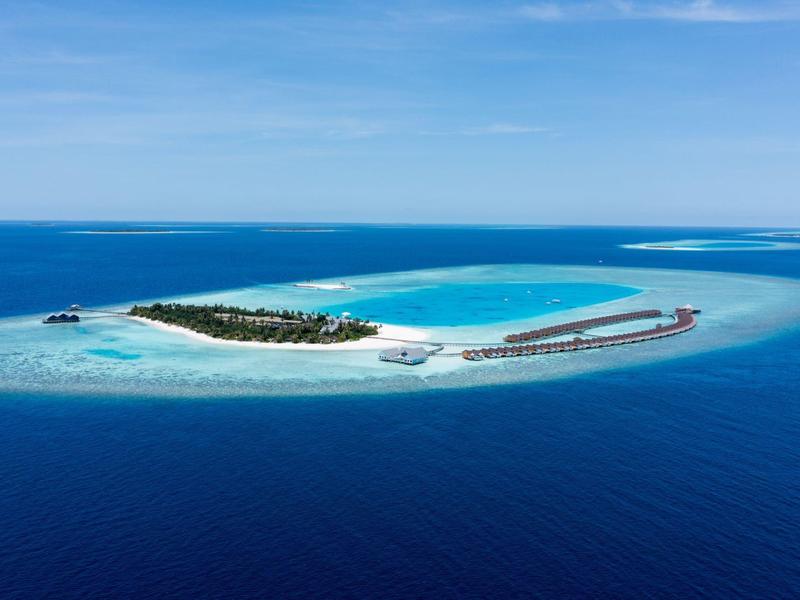 Klein tropisch eiland met wit zandstrand, lagune en watervilla's.