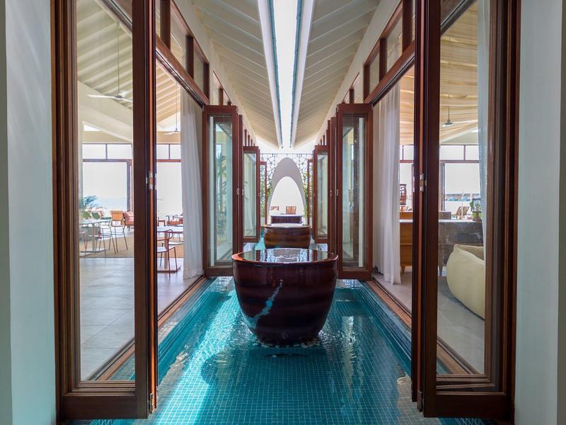 Uitzicht op een zwembadgang met open houten deuren en een boot in het water.