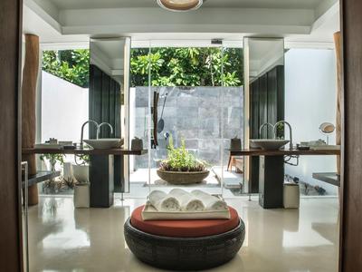 Salle de bain moderne avec doubles lavabos et assise ronde avec coussins.