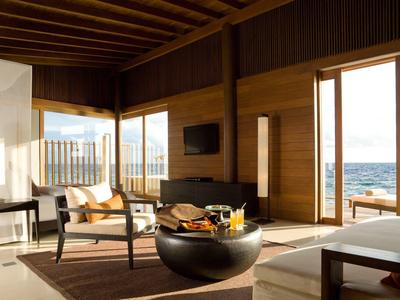 Chambre d'hôtel spacieuse avec grandes fenêtres donnant sur la mer et intérieur moderne.