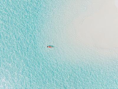 Nageur seul dans une eau turquoise avec une zone sablonneuse claire