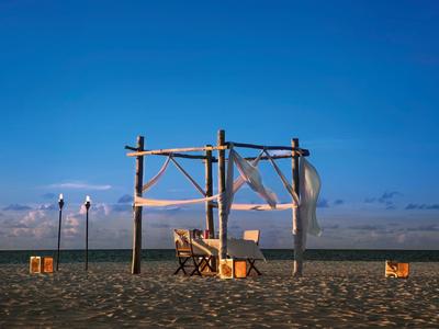 Pavillon de plage avec tables et chaises au coucher du soleil sous un ciel clair