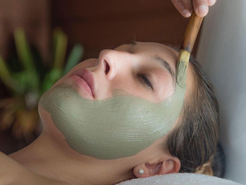 Femme détendue avec un masque facial vert lors d'un soin spa