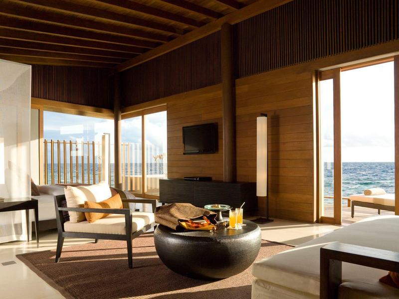 Chambre d'hôtel spacieuse avec grandes fenêtres donnant sur la mer et intérieur moderne.