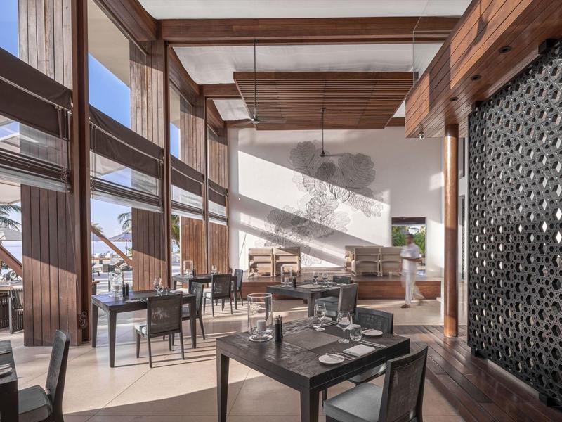 Restaurant moderne avec boiseries et grandes baies vitrées donnant sur la mer.