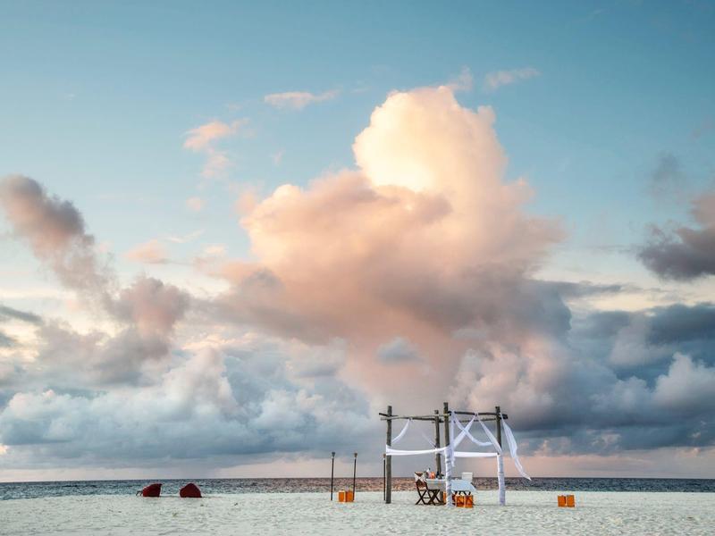 Plage avec ciel bleu et nuages, deux kayaks reposant sur le sable près d'une structure en bois.