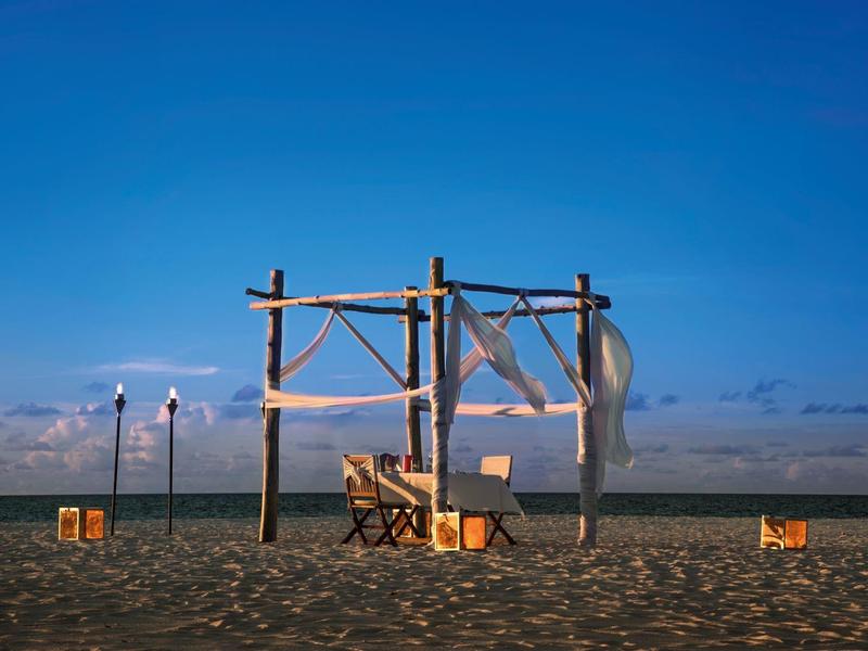Pavillon de plage avec tables et chaises au coucher du soleil sous un ciel clair