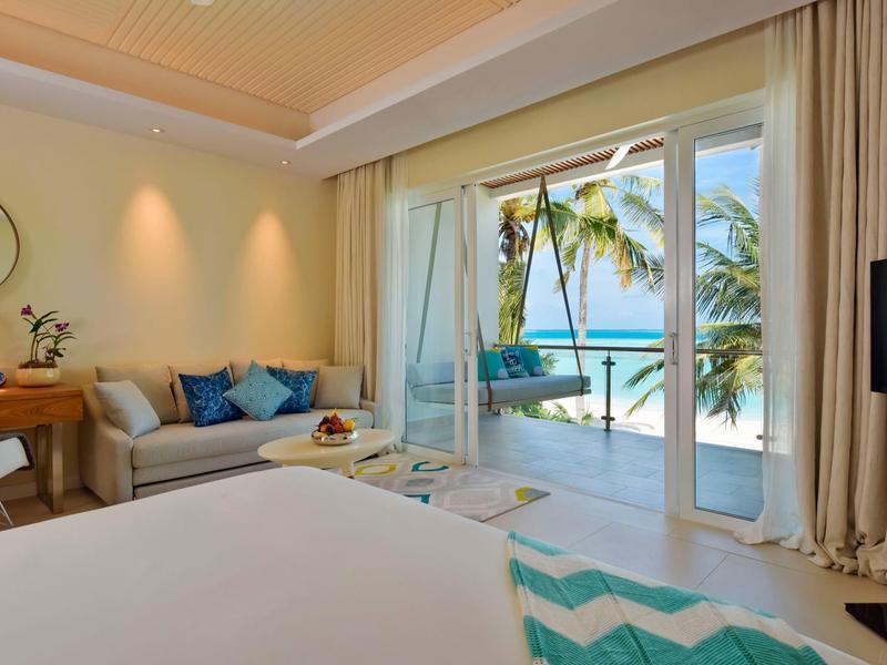 Helles Schlafzimmer mit Terrasse, Meerblick, tropischen Palmen und gemütlicher Sitzecke.