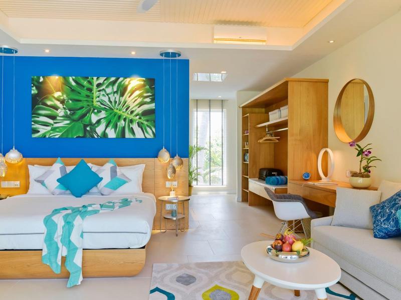 Modernes Wohnzimmer mit blauem Akzentwandbild, hellen Holzmöbeln und gemütlichen Sitzgelegenheiten.