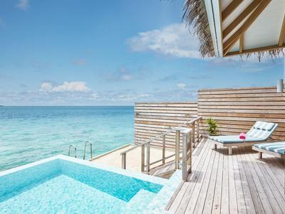 Privater Pool mit Blick auf das Meer und eine Liege auf einer Holzplattform.