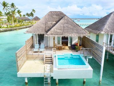 Überwasserbungalow mit Pool und Blick auf türkisfarbenes Wasser und Himmel.