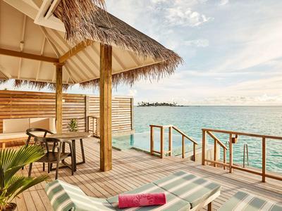Veranda mit Liegestuhl, Tisch und Meerblick bei sonnigem Himmel.