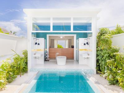 Moderner Wellnessbereich mit Pool, hellen Wänden und üppiger grüner Umgebung.