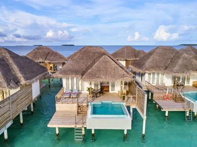 Luxuriöse Überwasserbungalows mit Pools im türkisfarbenen Meer unter blauem Himmel.
