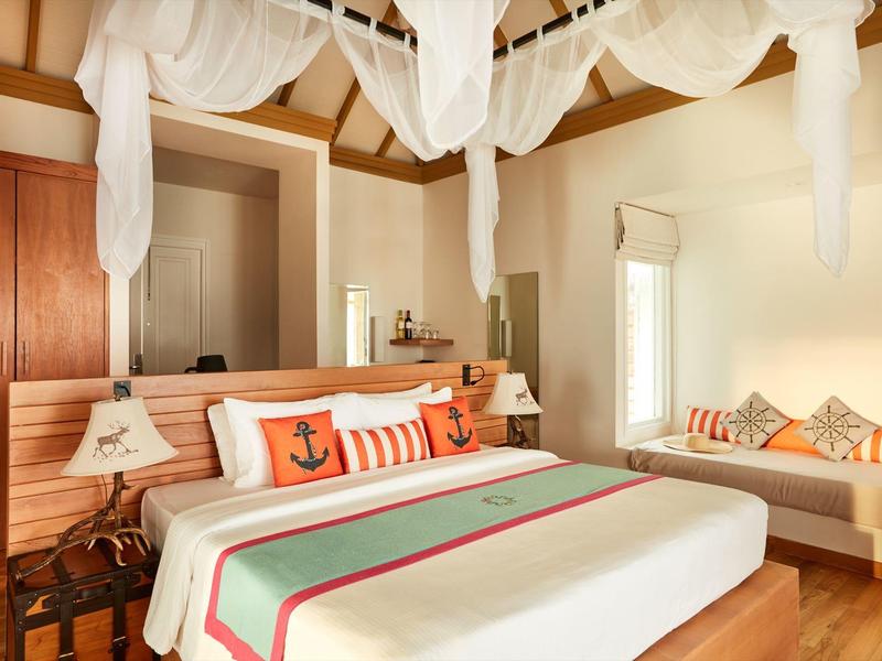 Luxuriöses Schlafzimmer mit großem Bett, Holzmöbeln und gemütlicher Sitzecke.