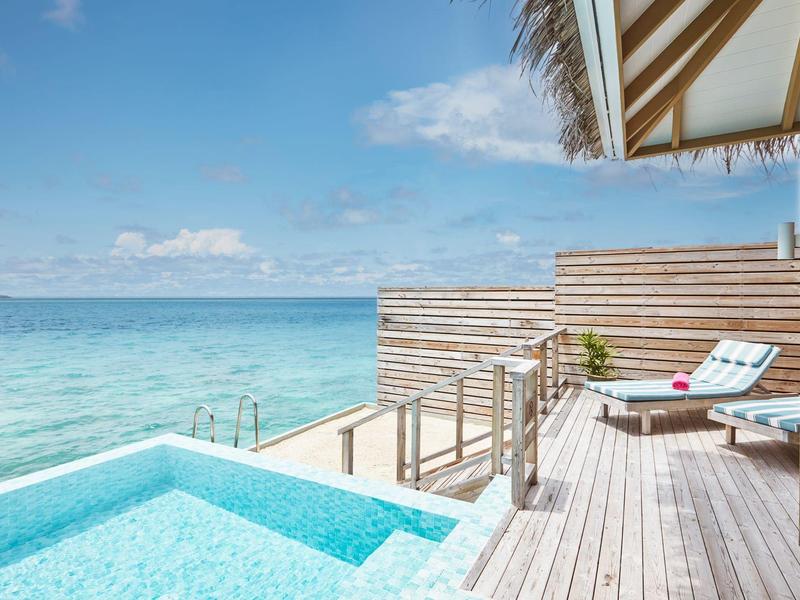Privater Pool mit Blick auf das Meer und eine Liege auf einer Holzplattform.