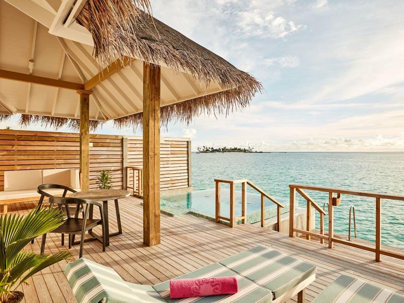 Veranda mit Liegestuhl, Tisch und Meerblick bei sonnigem Himmel.