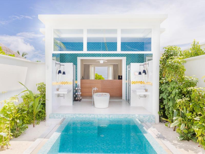 Moderner Wellnessbereich mit Pool, hellen Wänden und üppiger grüner Umgebung.