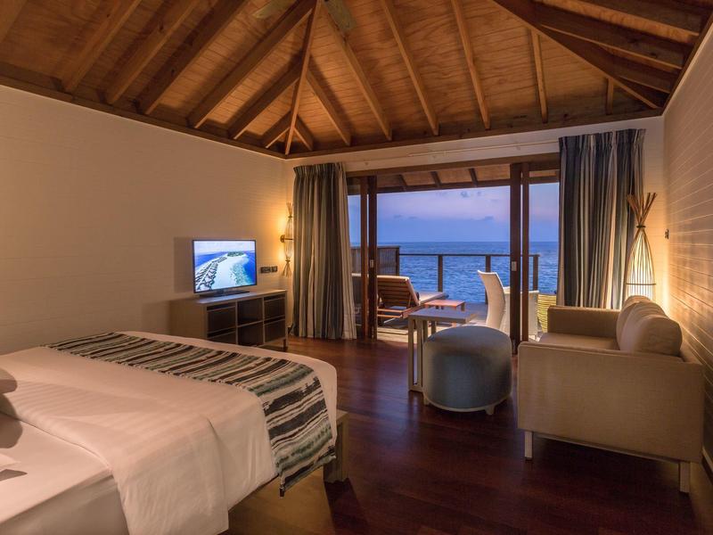Elegantes Hotelzimmer mit Doppelbett, Fernseher und Blick auf das Meer durch große Fenster