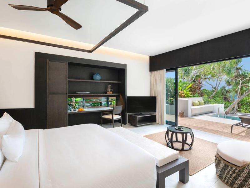 Moderner Hotelzimmer mit Doppelbett, Holzwand, TV, Sitzbereich und Terrasse mit Poolblick.