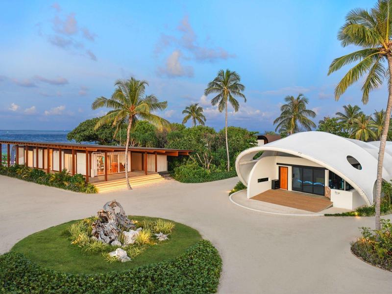 Moderne Bungalows in tropischer Umgebung mit Palmen und klarem Himmel.