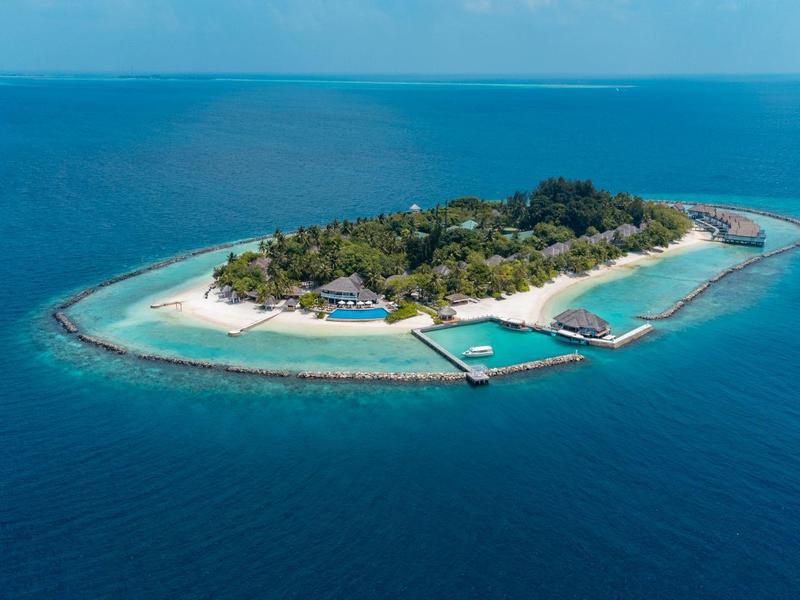 Kleine tropische Insel mit Sandstrand, Vegetation und Bootsanleger im blauen Ozean.