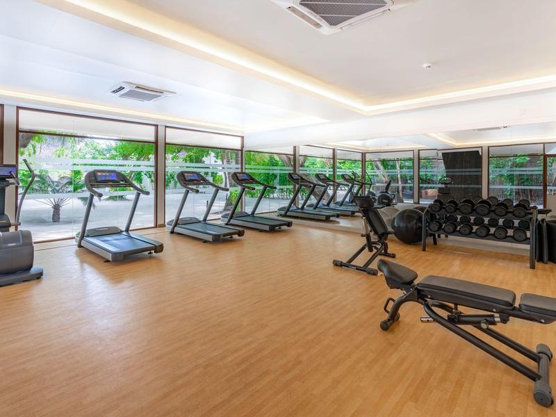 Moderner Fitnessraum mit Laufbändern, Hanteln und Panoramafenstern mit Außenblick.