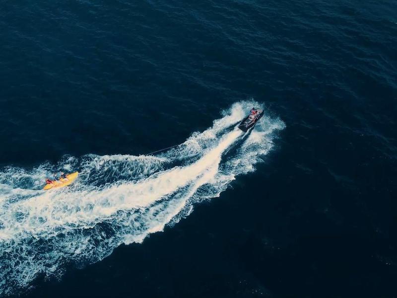 Ein Jetski fährt schnell über das dunkle, leicht wellige Wasser und hinterlässt weiße Gischt.