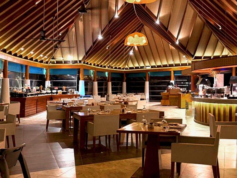 Großes, rundes Restaurant mit Holzdecke, weißen Stühlen, Tischen und warmem Licht.