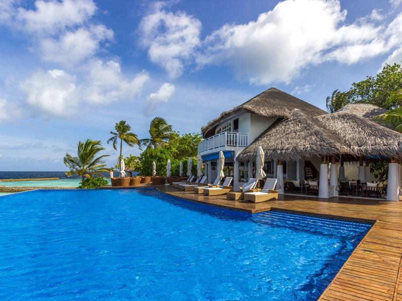 Luxuriöses Hotel mit großem Pool und Blick auf das Meer unter blauem Himmel.